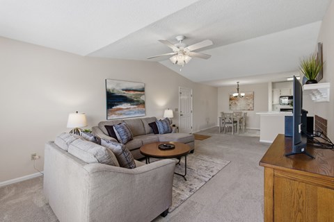 A living room with a grey couch and a painting on the wall.