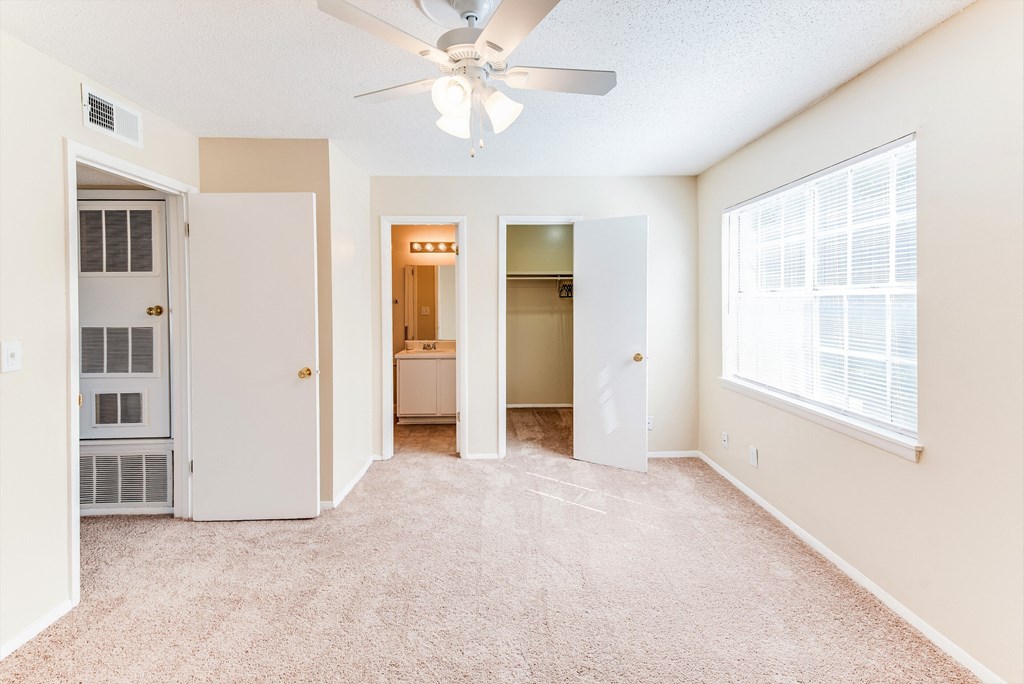 an empty living room with a ceiling fan and a window