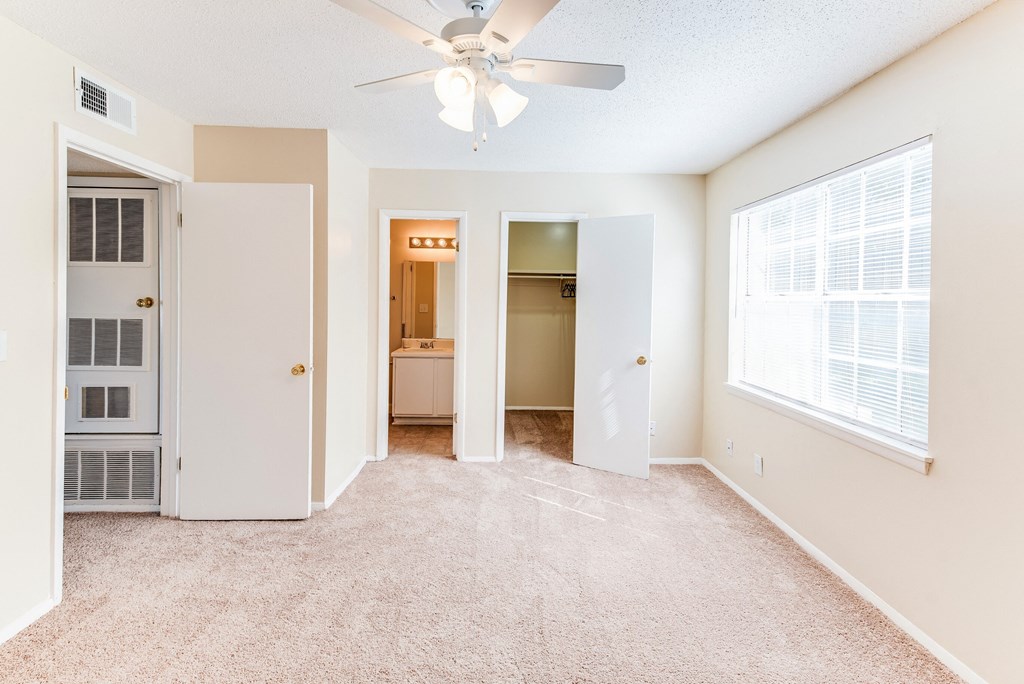 an empty living room with a ceiling fan and a window
