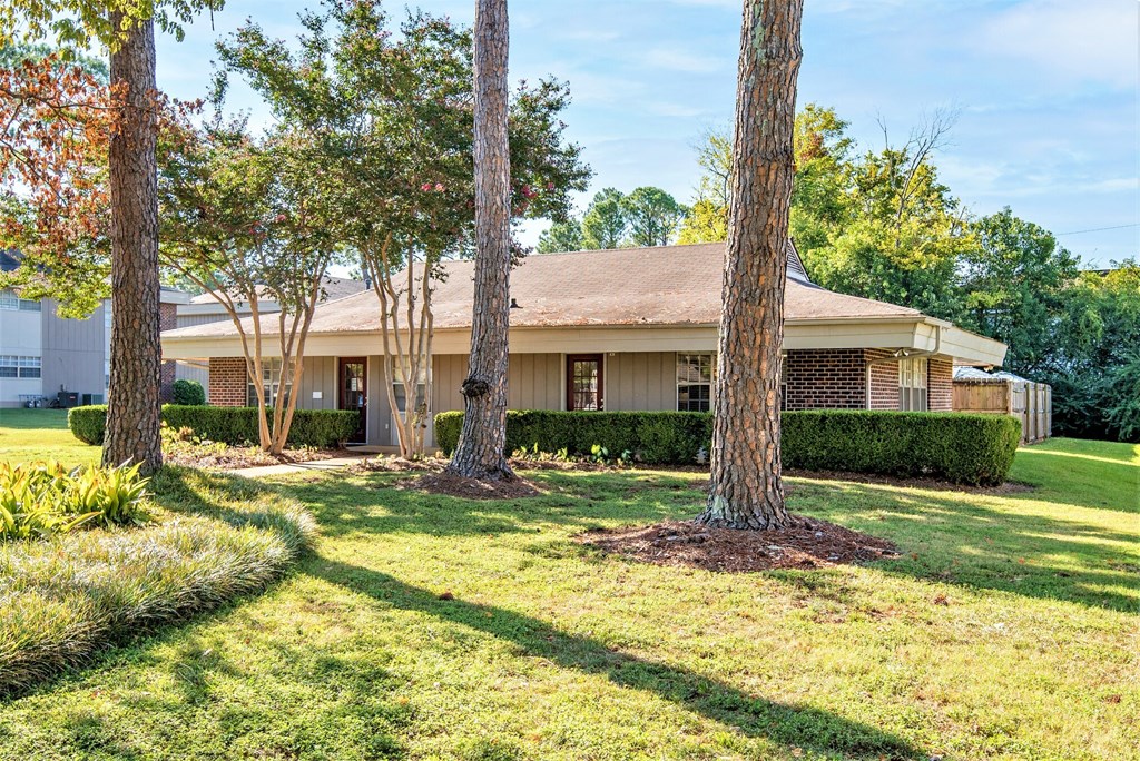 a house with a yard and trees in front of it
