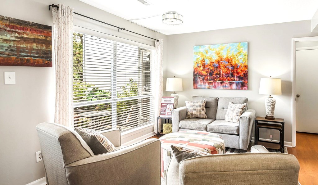 A living room with a couch, chair, and a painting on the wall.