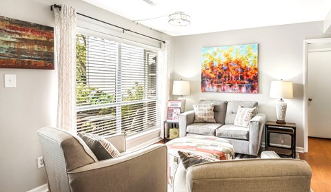 A living room with a couch, chair, and a painting on the wall.