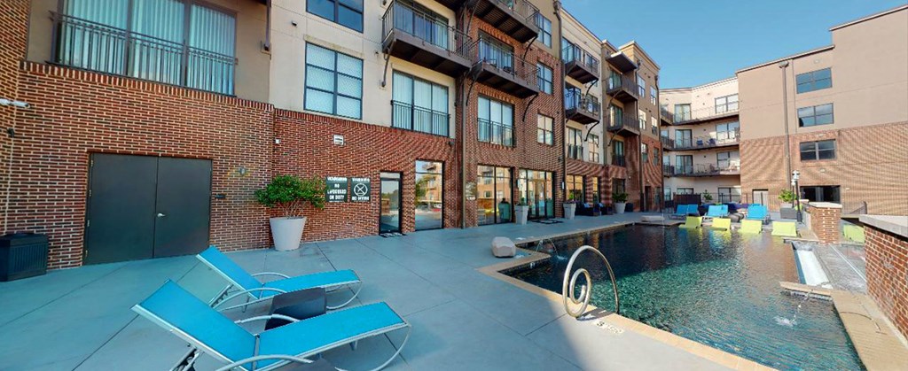 an apartment building with a pool and lounge chairs