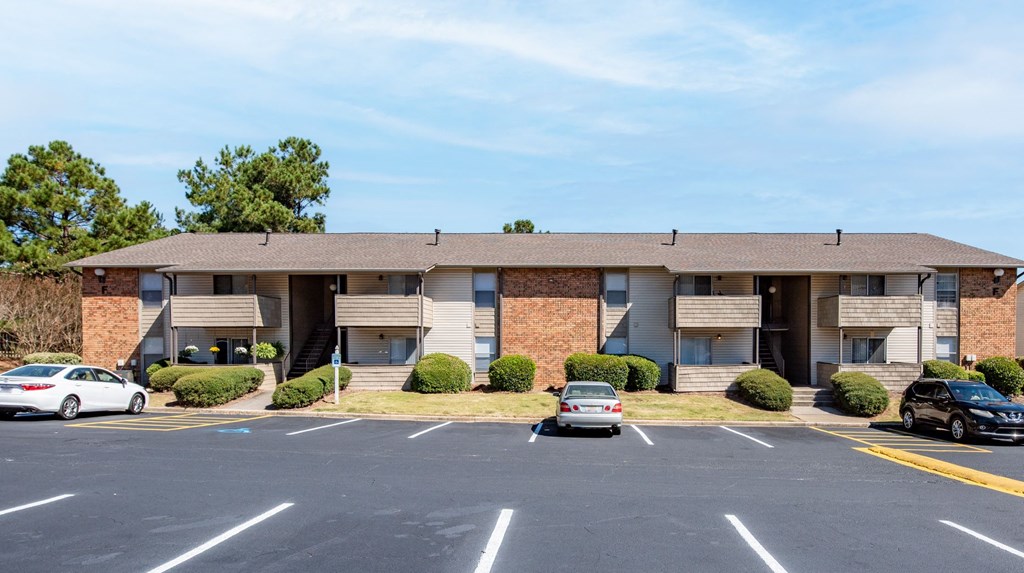 an apartment building with cars parked in a parking lot