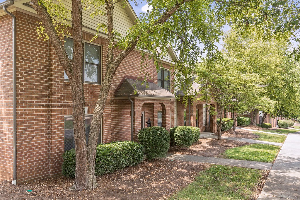 a brick building with a sidewalk and trees