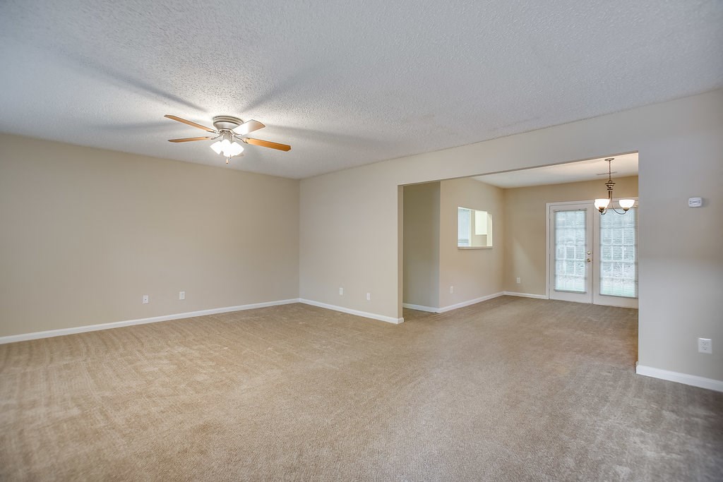 an empty living room with a ceiling fan and a window
