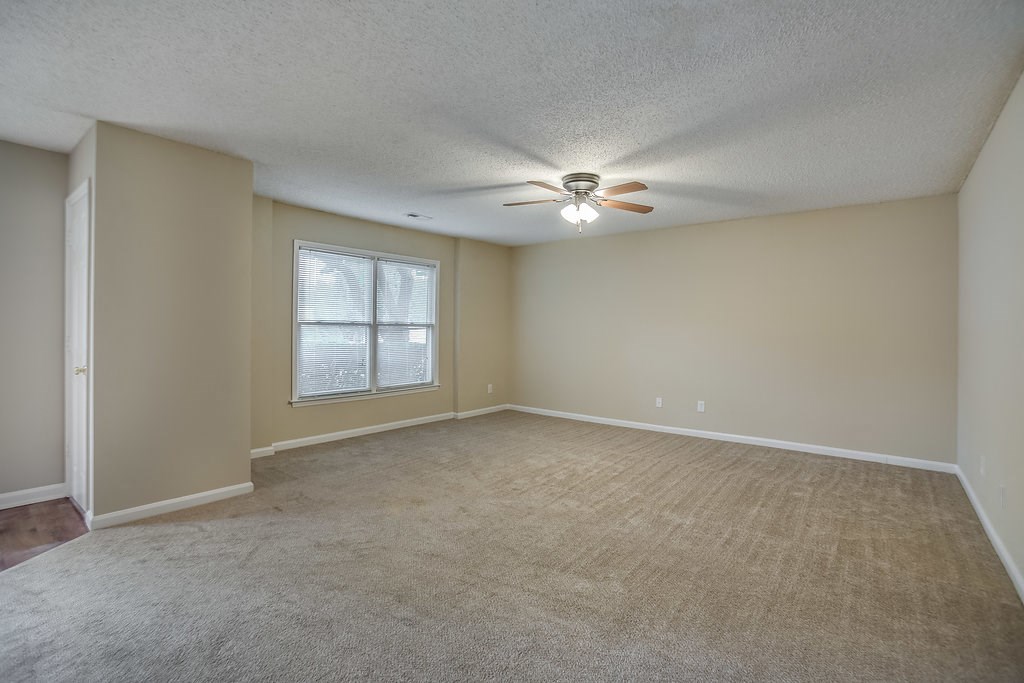 an empty living room with a ceiling fan and a window