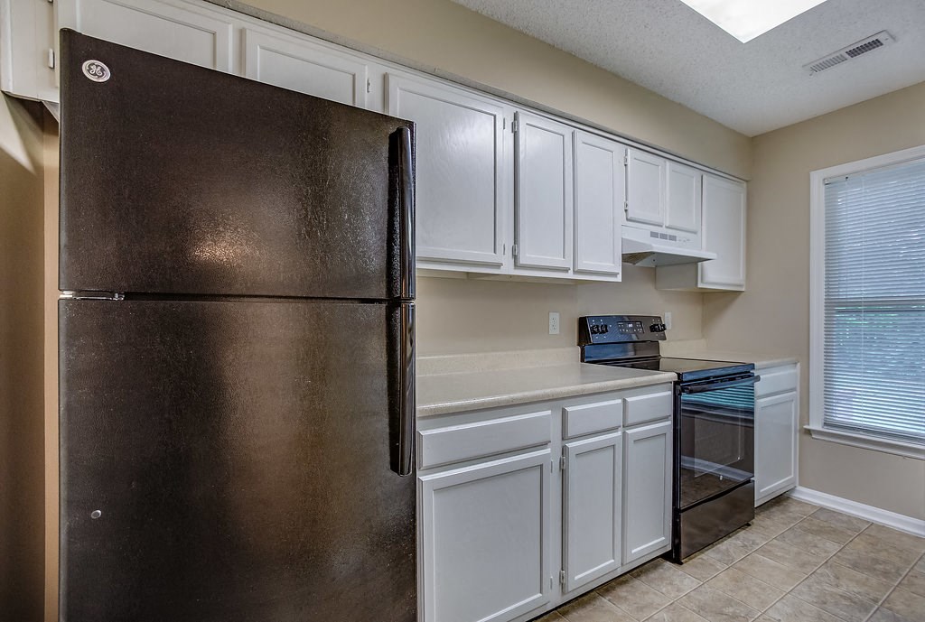 a kitchen with white cabinets and a stainless steel refrigerator