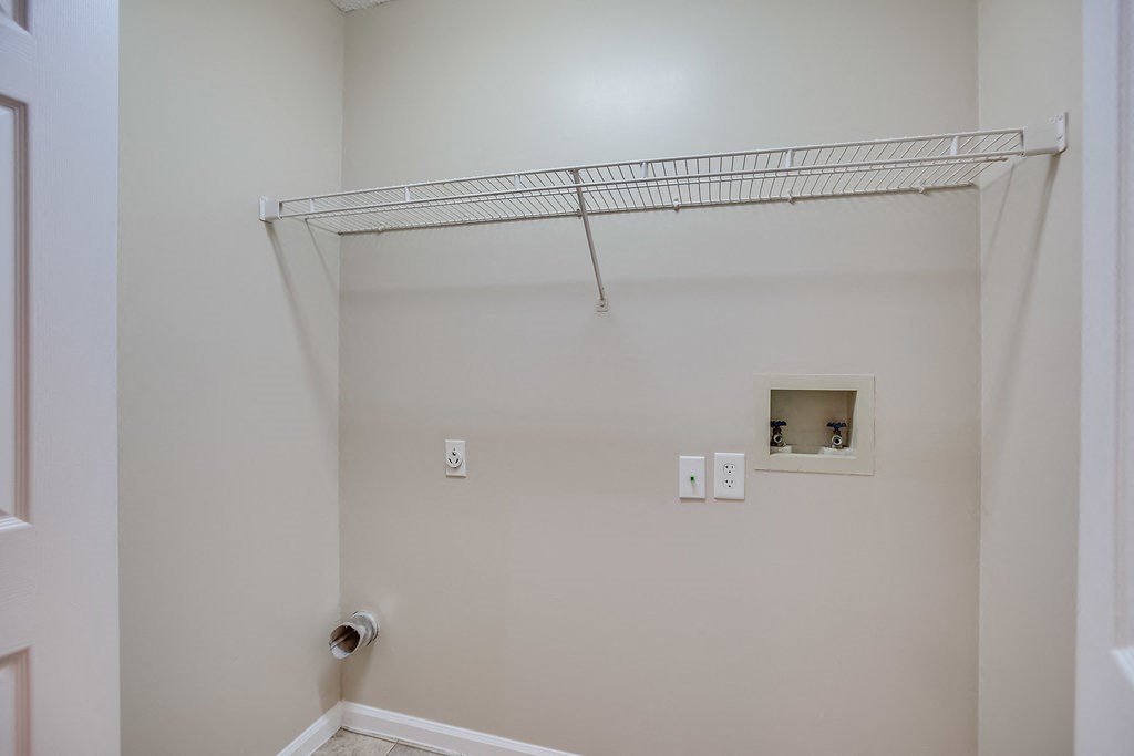 a white bathroom with a shower and a wire shelf on the wall