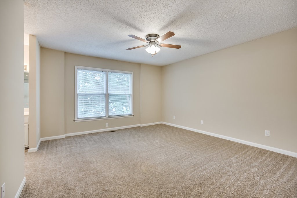 an empty living room with a ceiling fan and a window