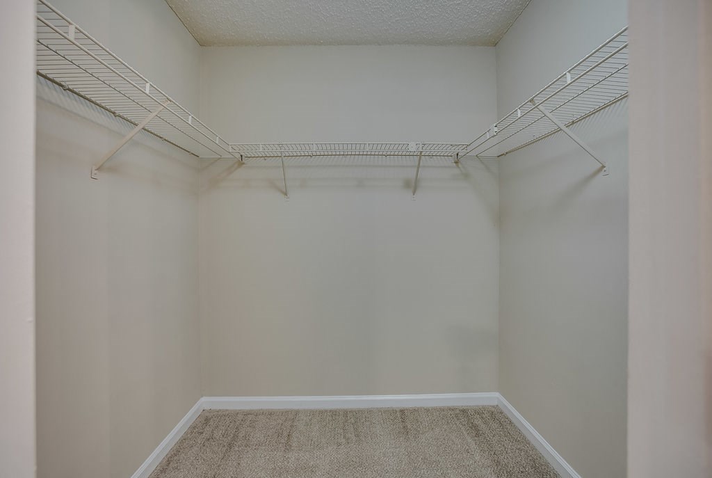 an empty closet with white walls and a wire rack on the ceiling