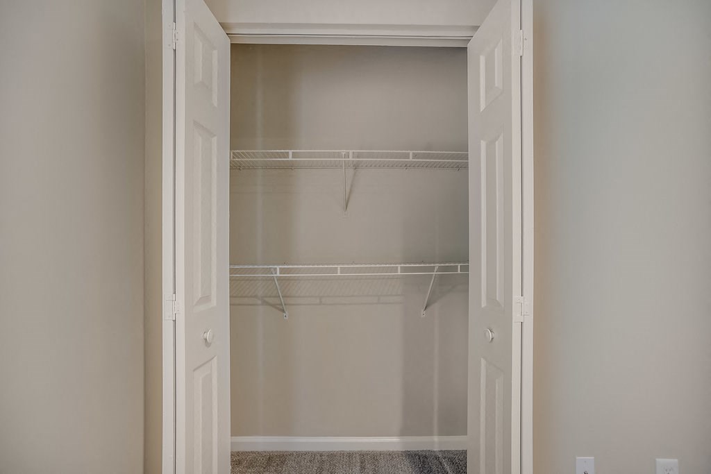 an empty closet with empty shelves in a home with white doors