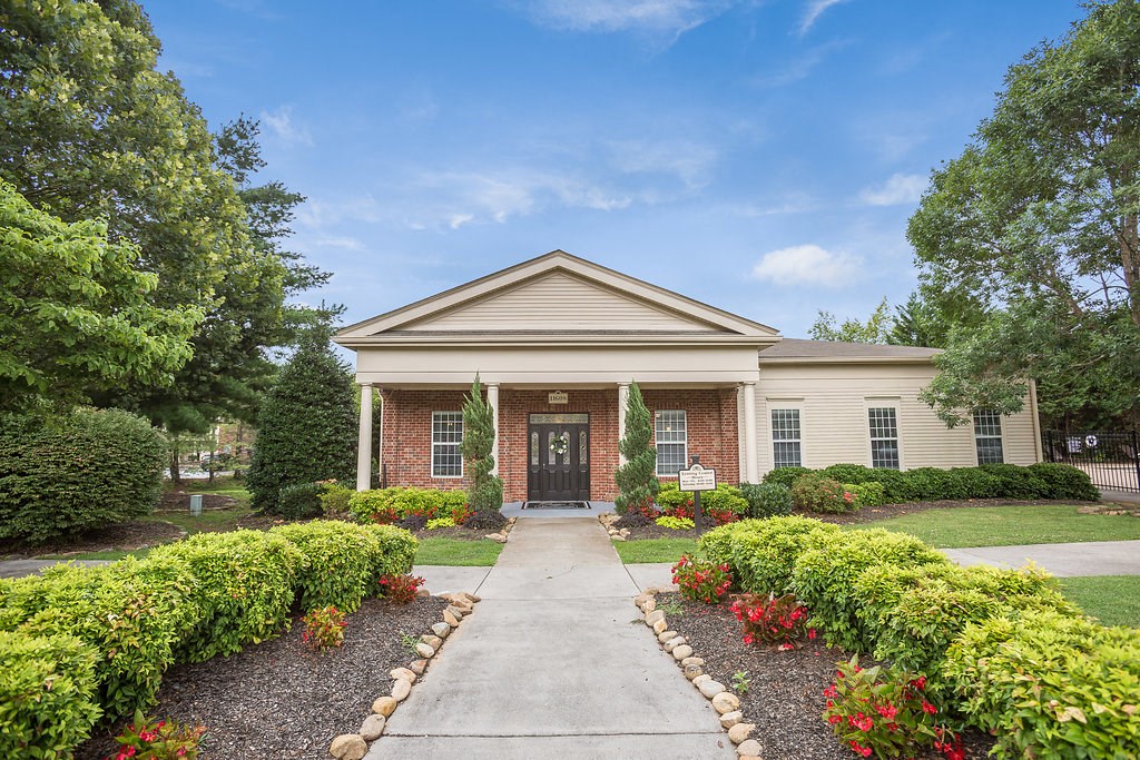 the front of a brick house with a sidewalk and landscaping