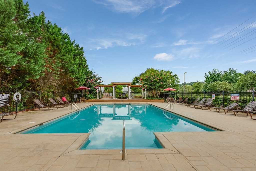 a swimming pool with chairs and umbrellas at the resort on a sunny day