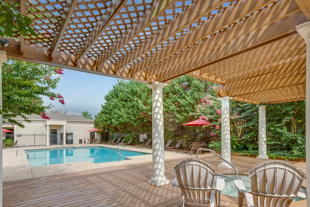a swimming pool with chairs under a patio
