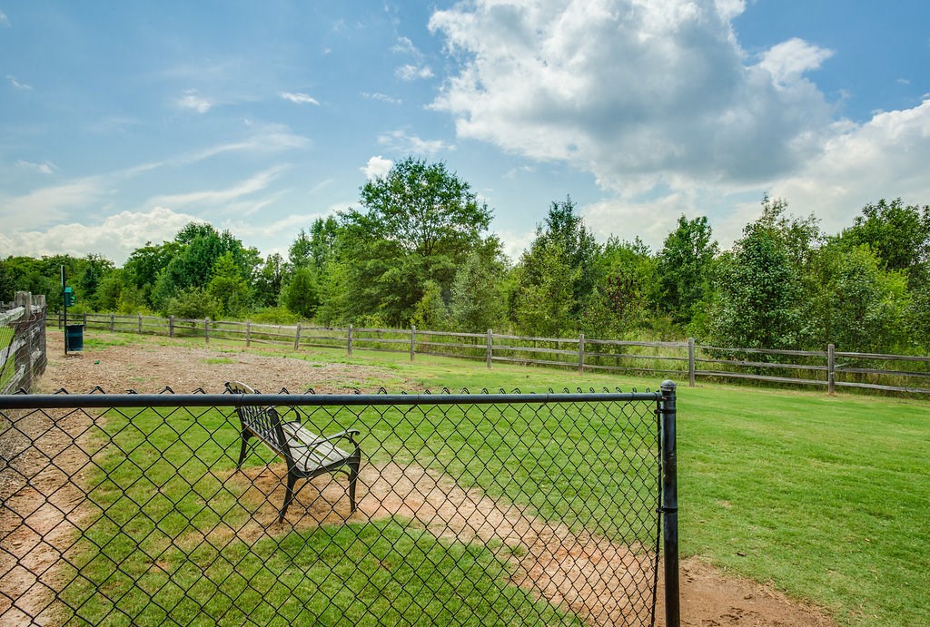 a park bench in the middle of a field behind a fence