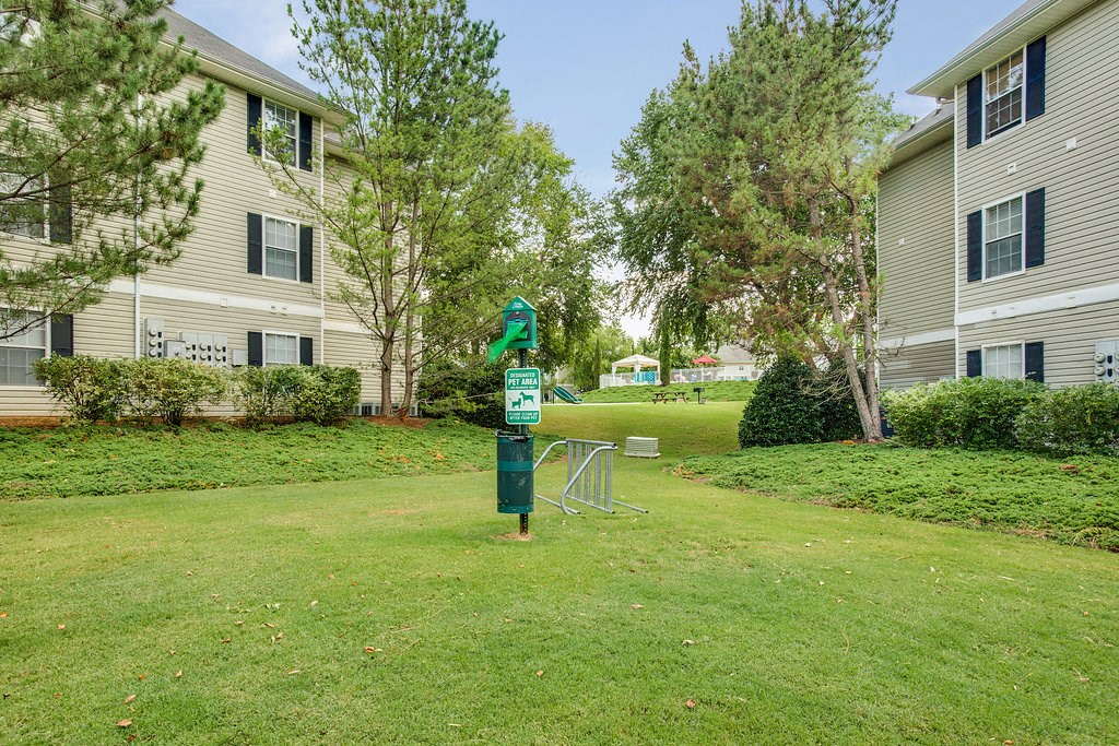 a green parking meter in the middle of a yard between two apartment buildings