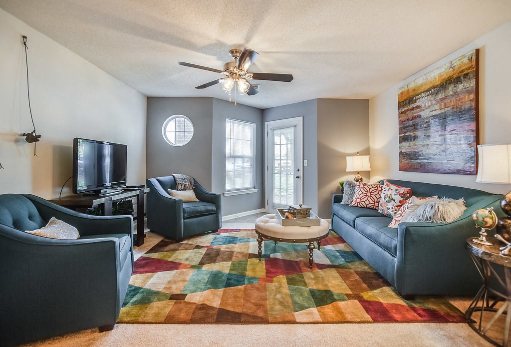 a living room with couches and chairs and a ceiling fan