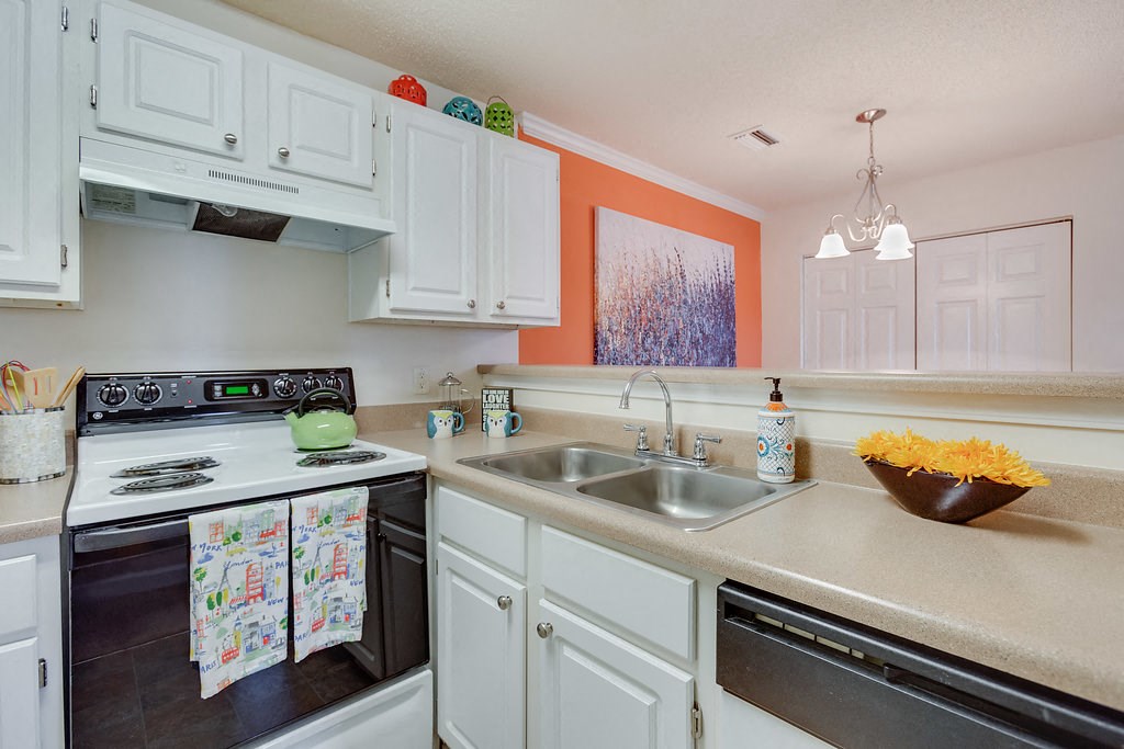 a kitchen with white cabinets and black appliances and a sink
