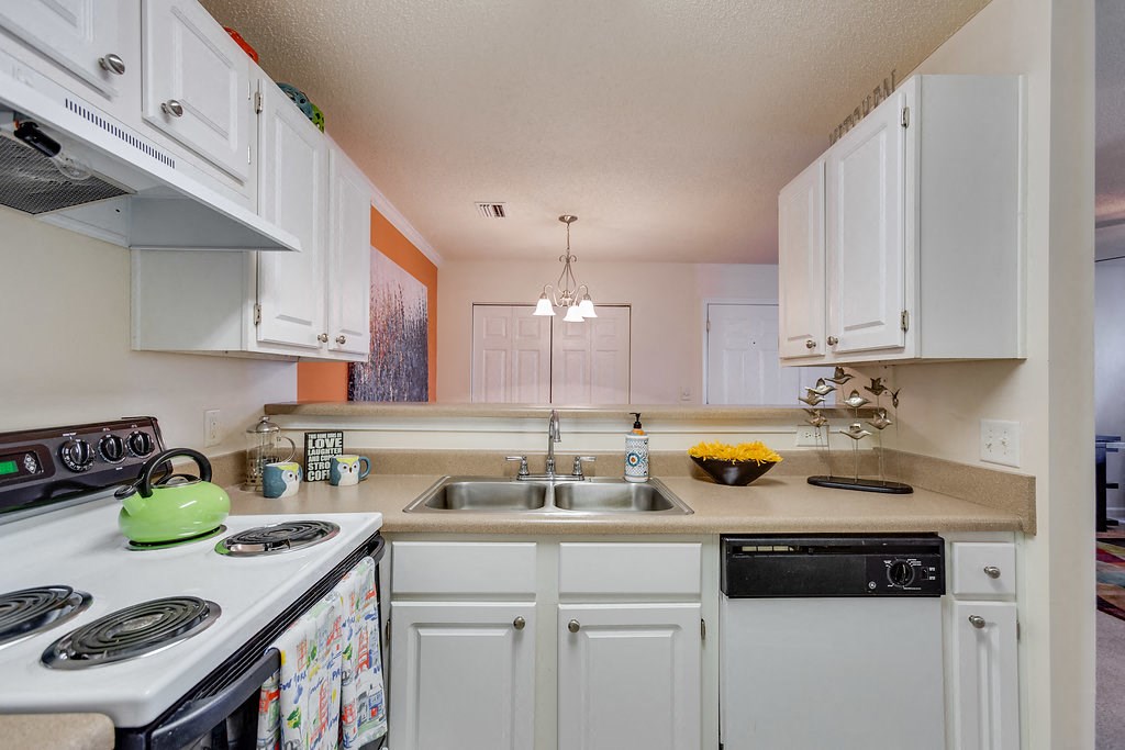 a kitchen with white cabinets and appliances and a sink
