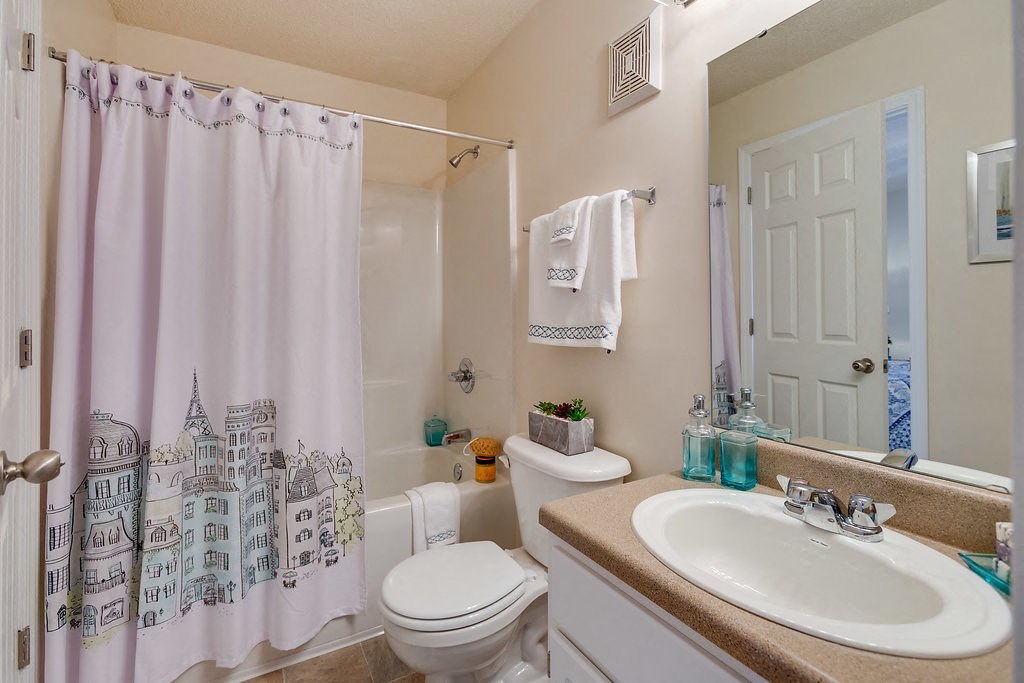 a bathroom with a shower curtain and a toilet and sink