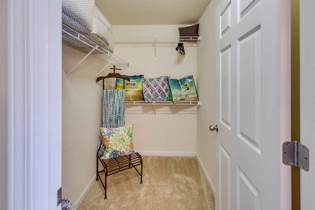 a walk in closet with a chair and shelves