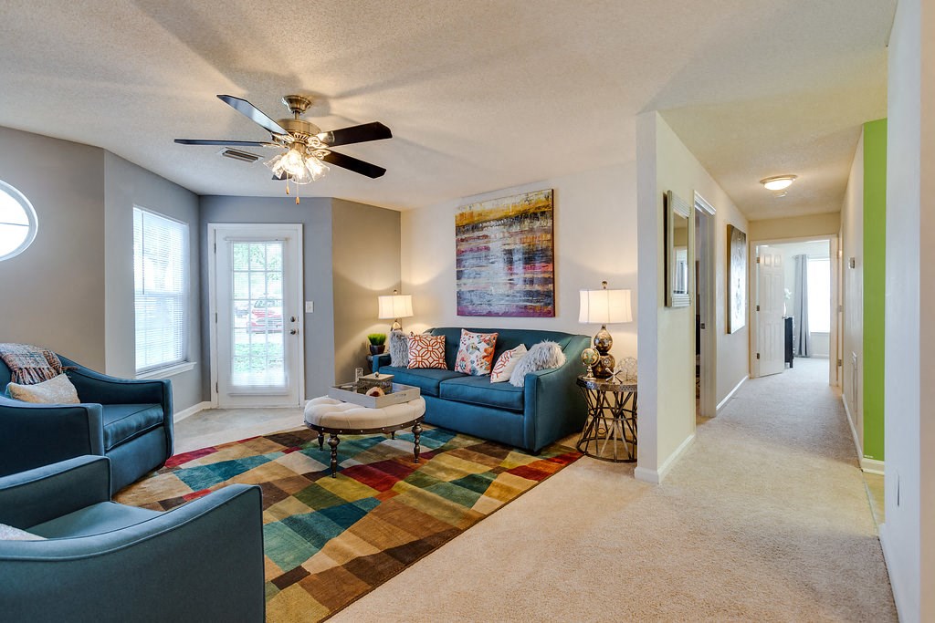 a living room with blue furniture and a ceiling fan
