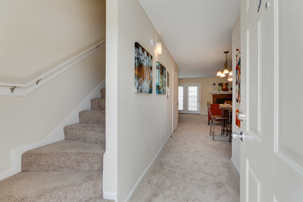 a view of a hallway with stairs and a dining room