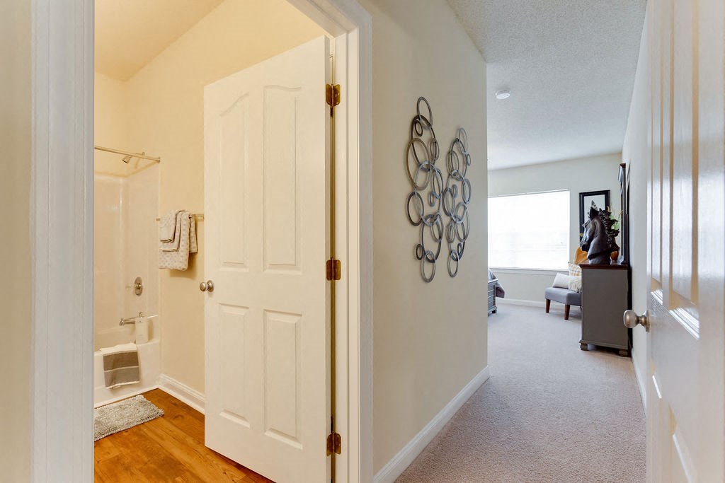 a hallway with a door to a bathroom and a living room