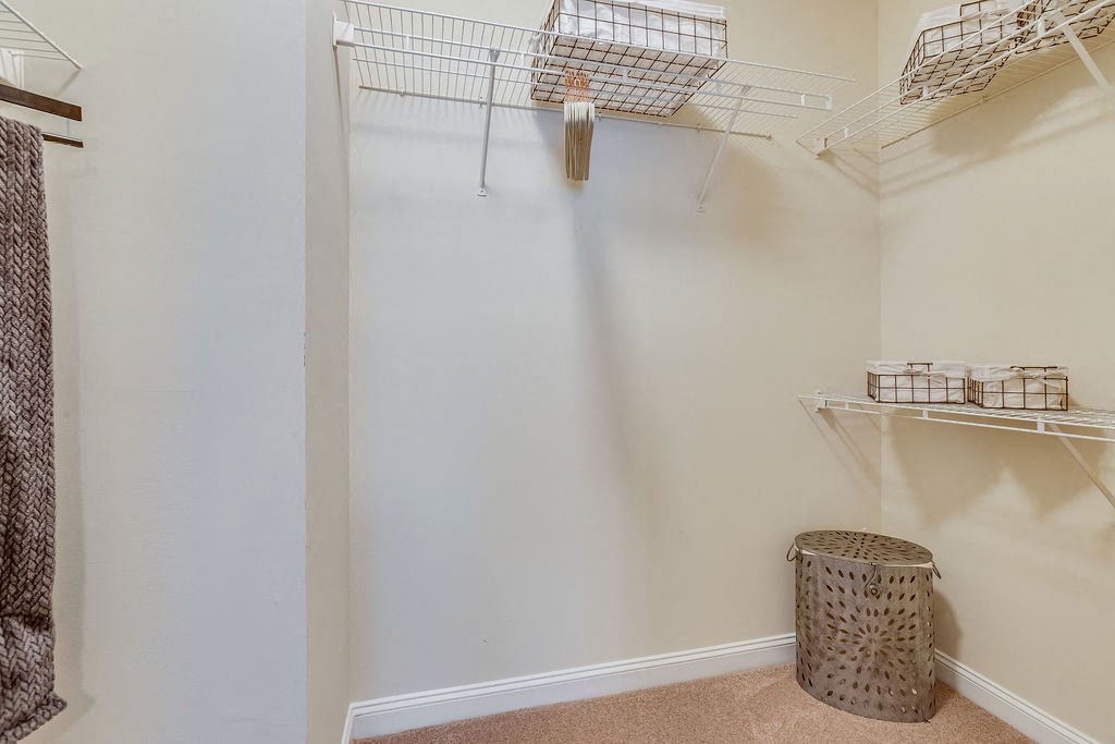 a walk in closet with shelves and a trash can