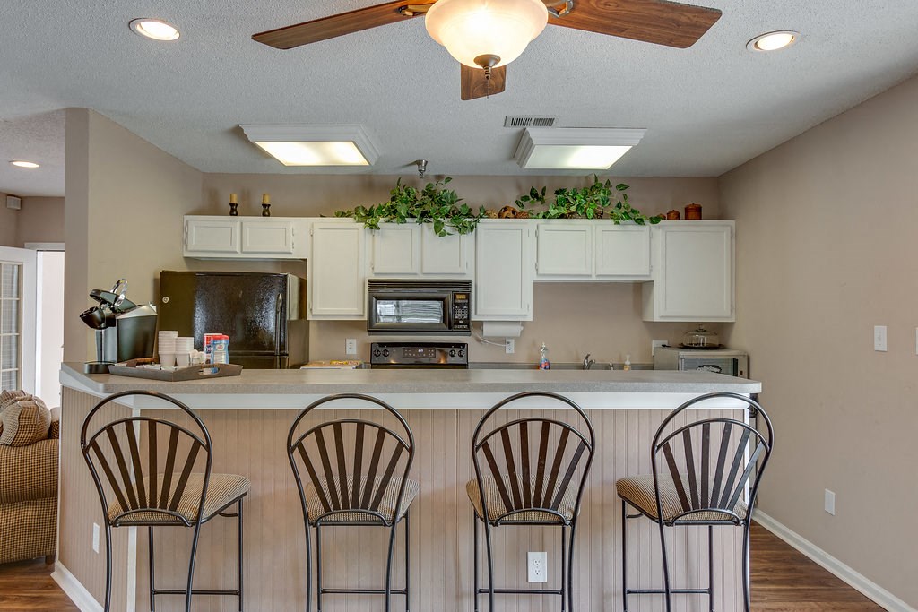 a kitchen with a bar with three chairs