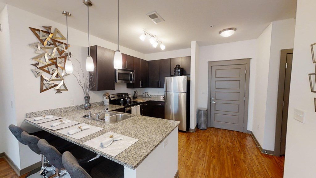 a kitchen with a granite counter top and a stainless steel refrigerator