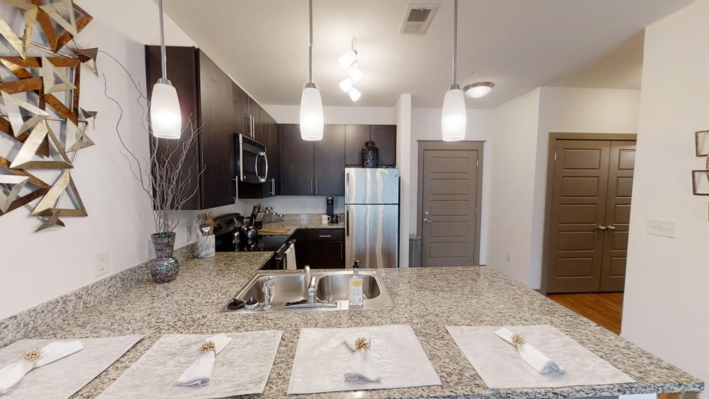 a kitchen with granite counter tops and a stainless steel refrigerator