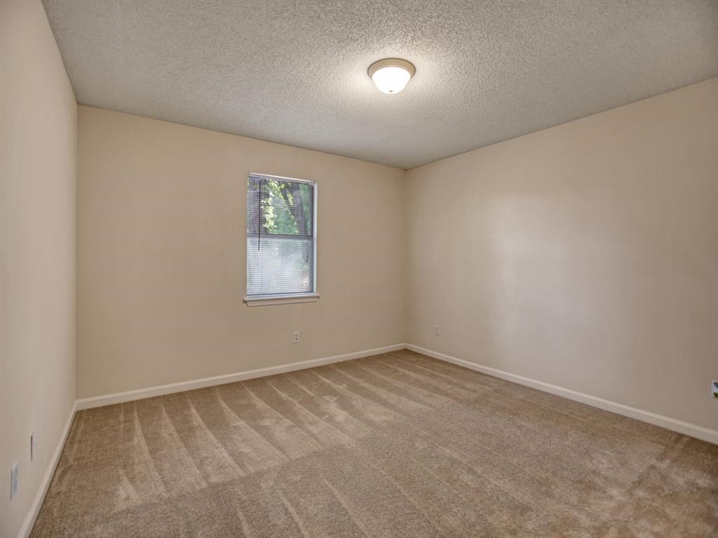 an empty living room with carpet and a window