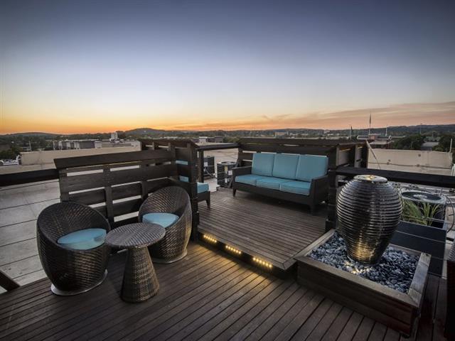 a rooftop deck with a blue couch and chairs