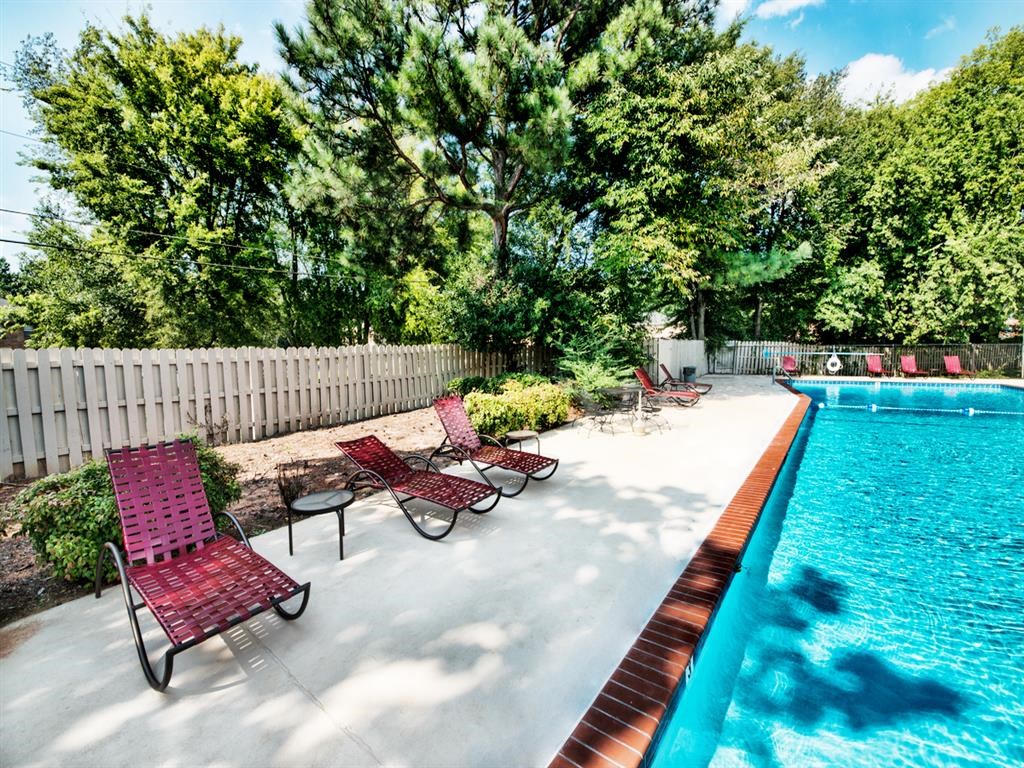 a swimming pool with chaise lounge chairs and a privacy fence