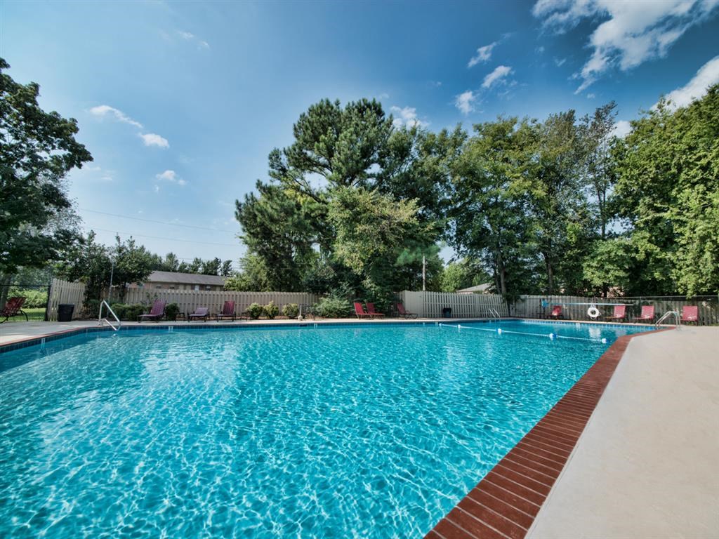 a large swimming pool with trees in the background
