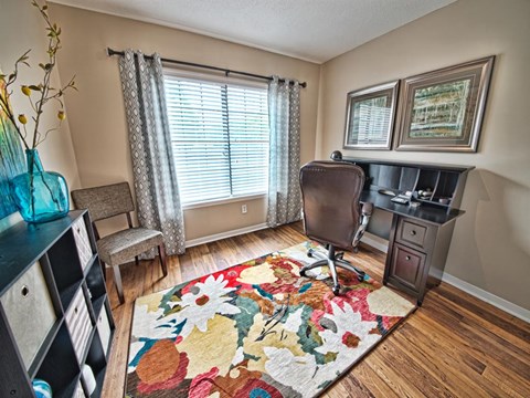a living room with a rug and a desk with a chair