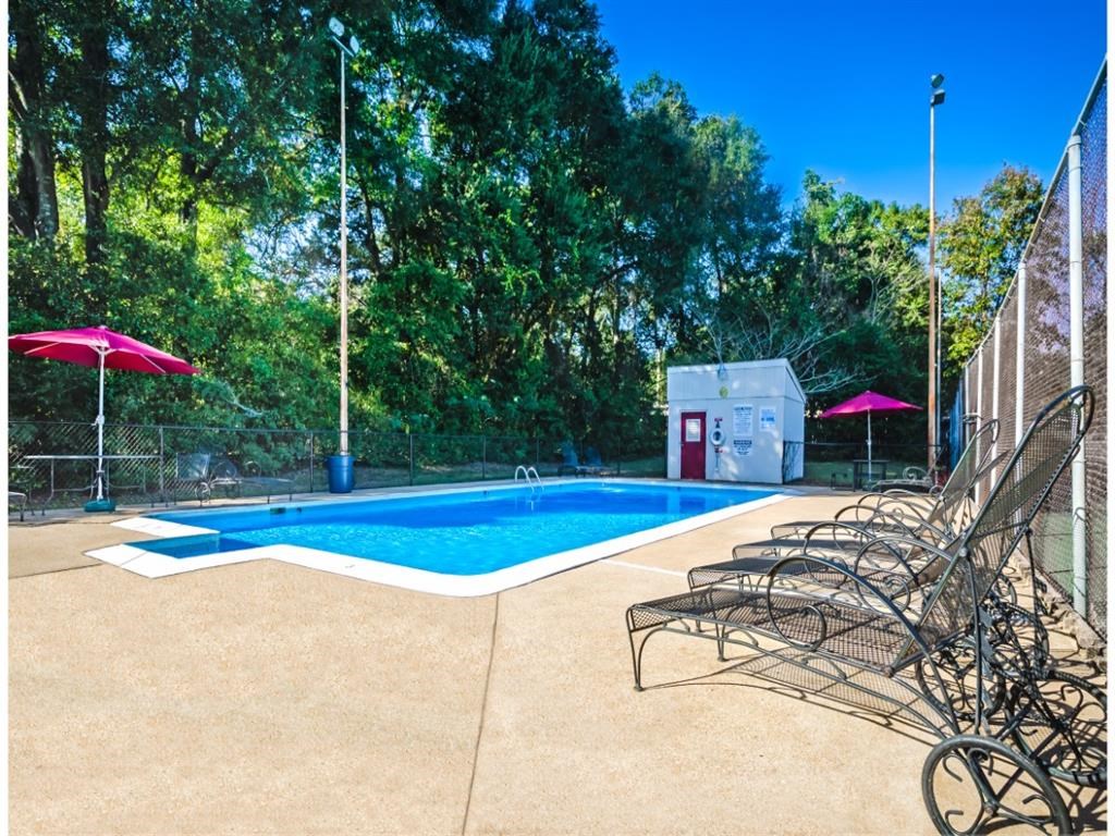 a swimming pool with chairs around it and a poolside hot tub
