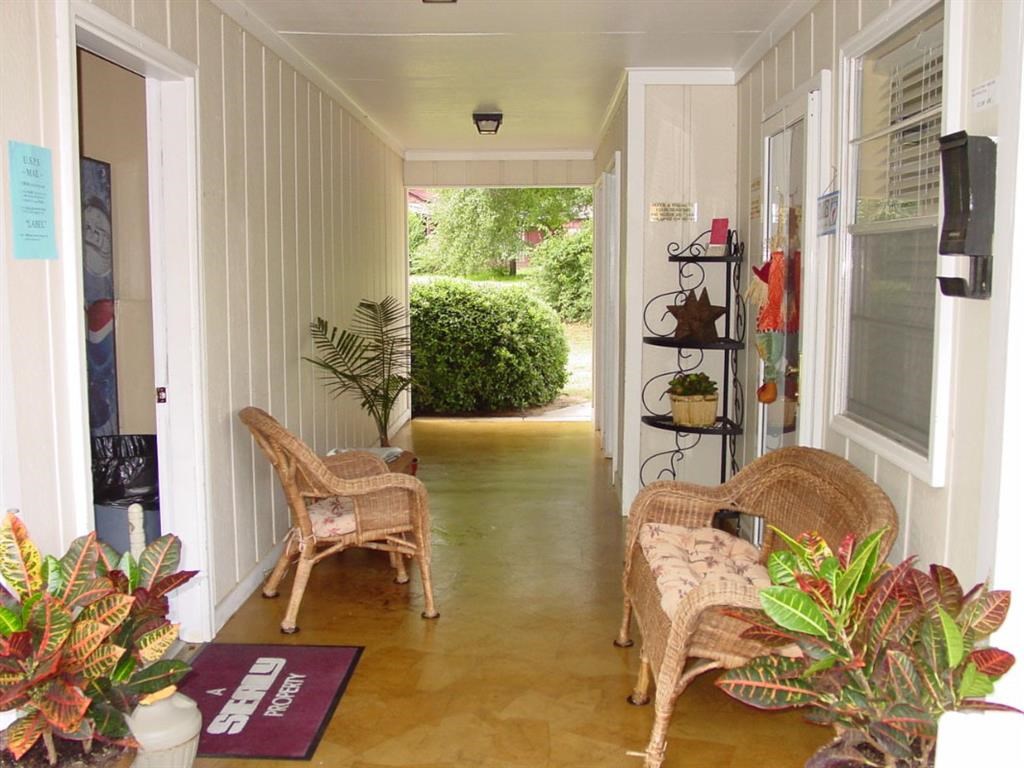 a porch with two wicker chairs and a door