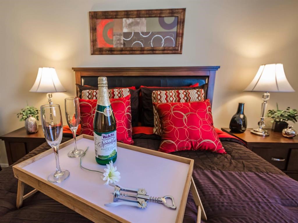 a bedroom with a bed and a bottle of wine on a table