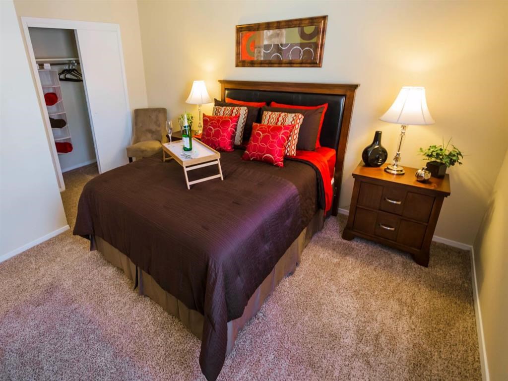 a bedroom with a bed and two night stands and a closet