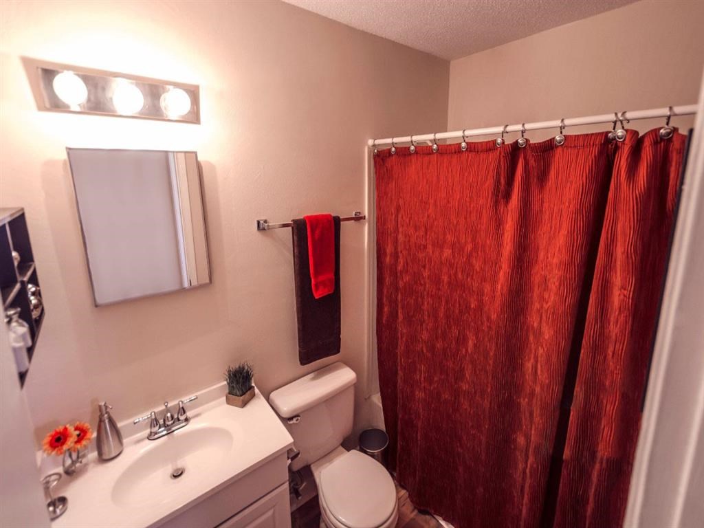a bathroom with a red shower curtain and a toilet and sink