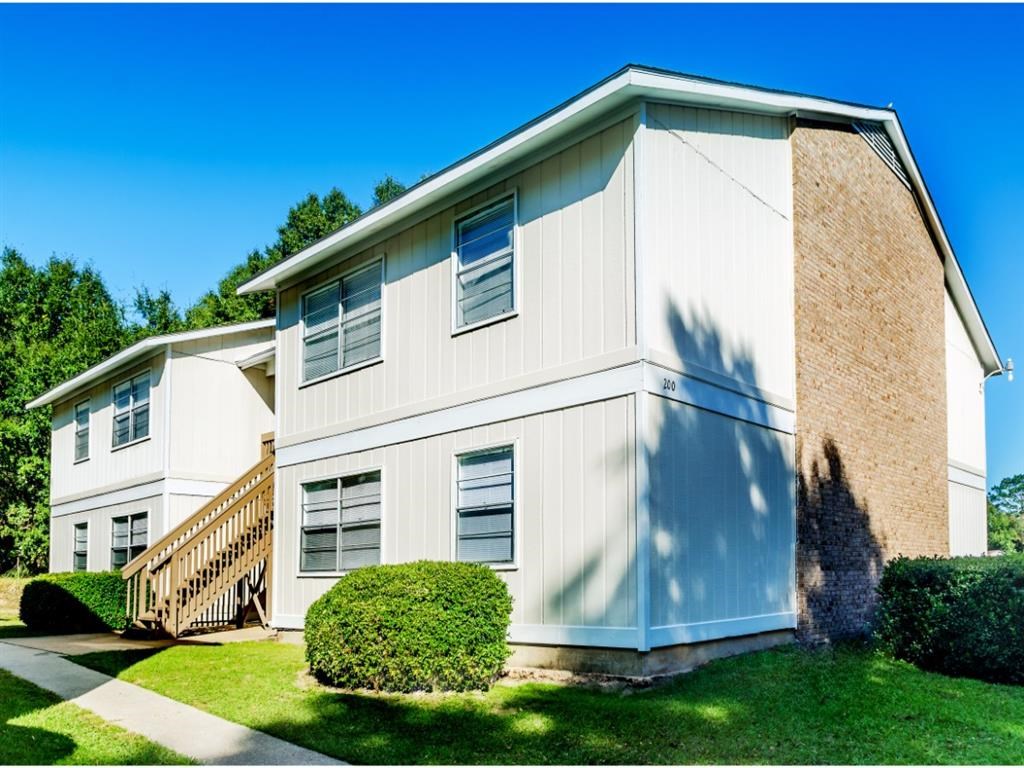 a white and brick house with a sidewalk and a staircase