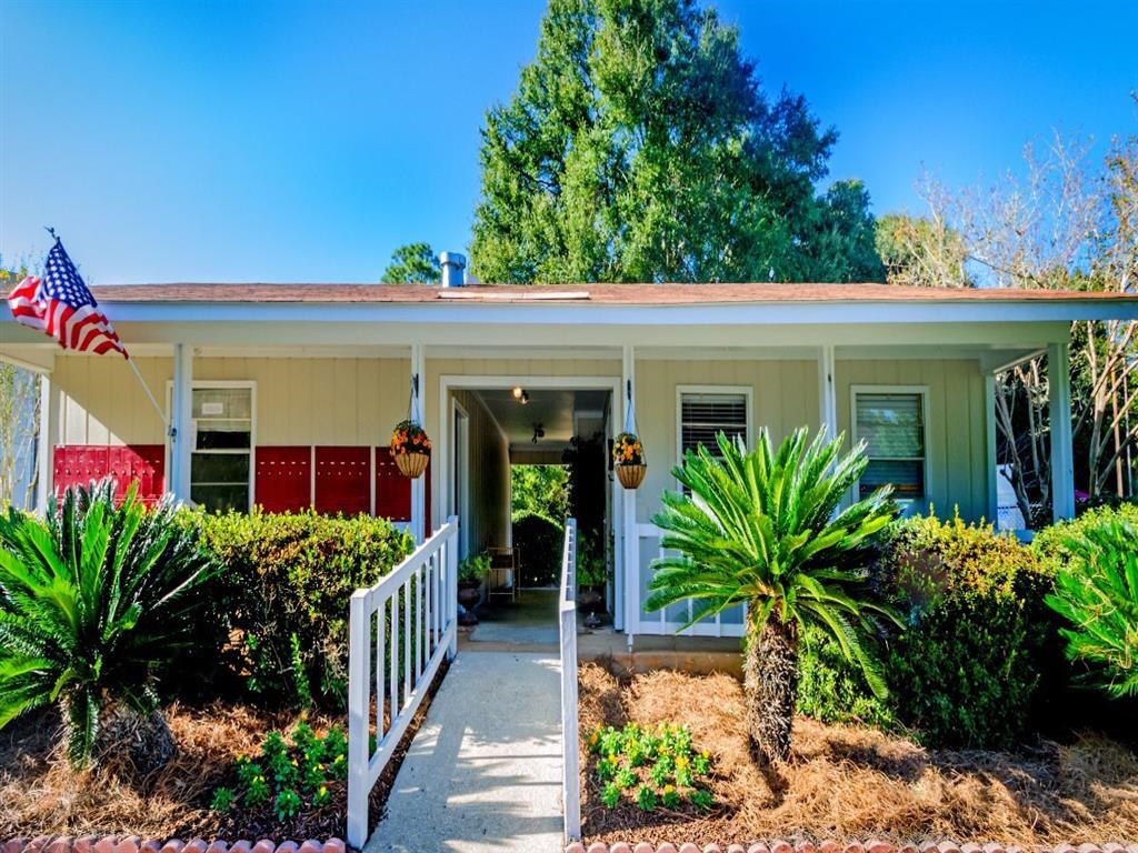 a white house with a porch and a flag in front of it