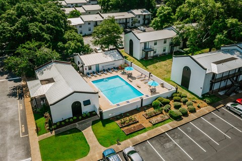 A large white building with a pool in the middle of a grassy area.