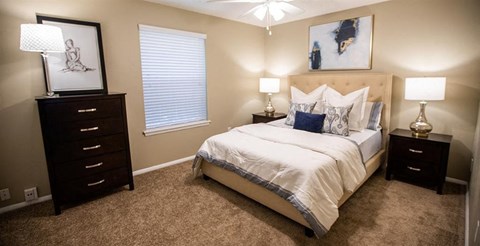 A bedroom with a bed, nightstands, and a painting on the wall.