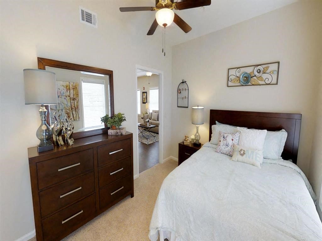 a bedroom with a bed and a dresser and a ceiling fan