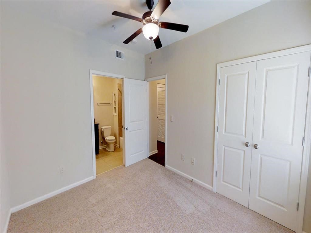 a bedroom with a ceiling fan and a door to a bathroom