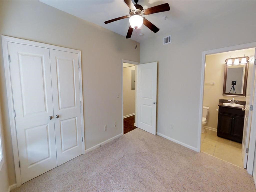 an empty bedroom with a ceiling fan and a closet